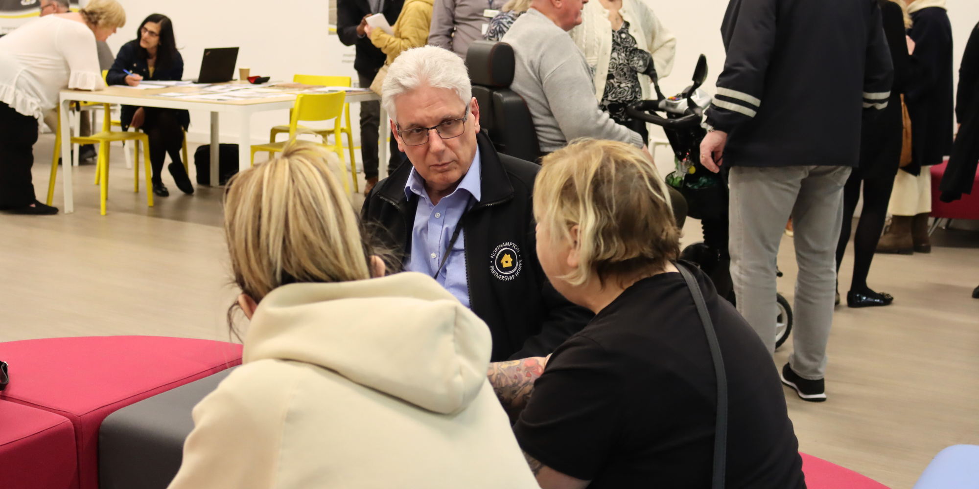 Housing Support Drop In 2025 NPH Officer is sitting and talking with two residents